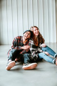 A man and a woman sitting on the floor laughing